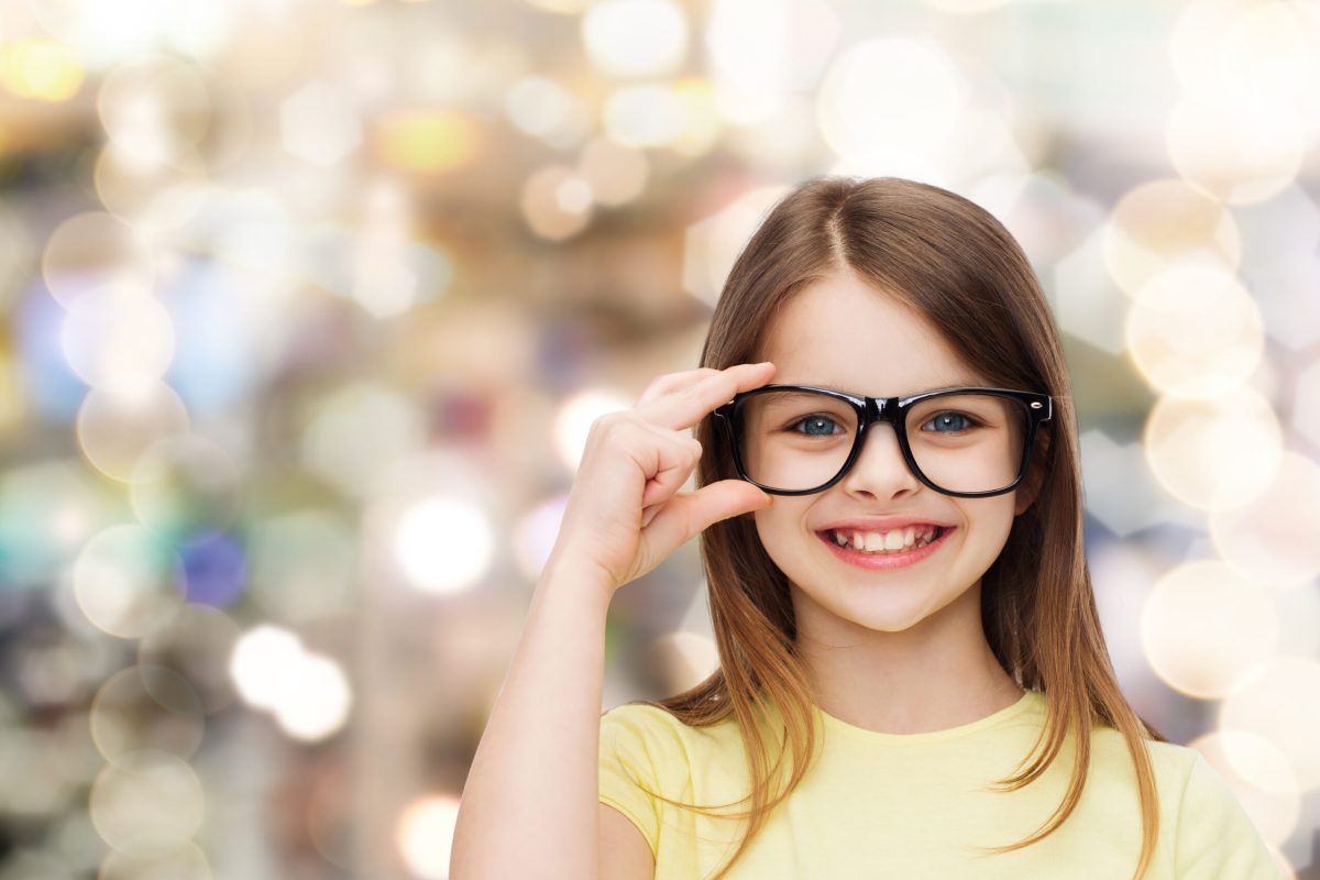 education, school and vision concept - smiling cute little girl in black eyeglasses