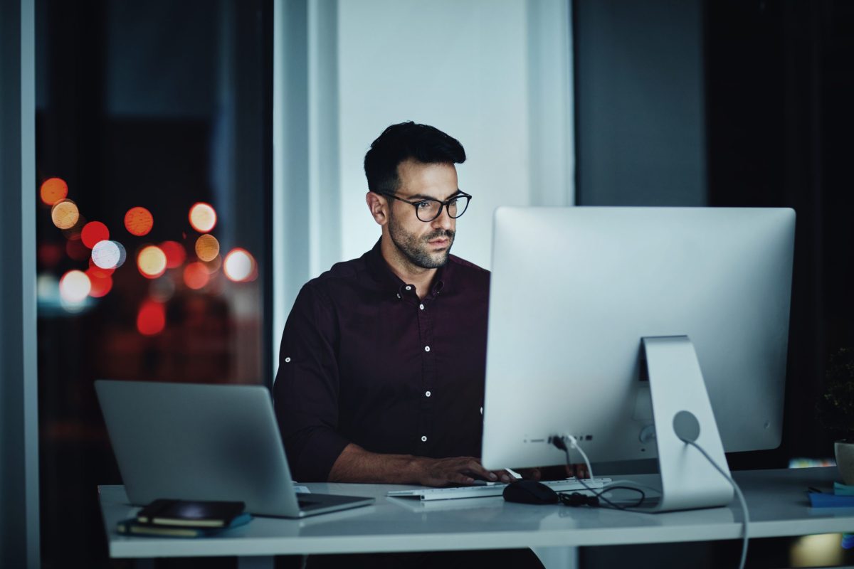 Shot of a young businessman using a computer at his desk during a late night at work.
